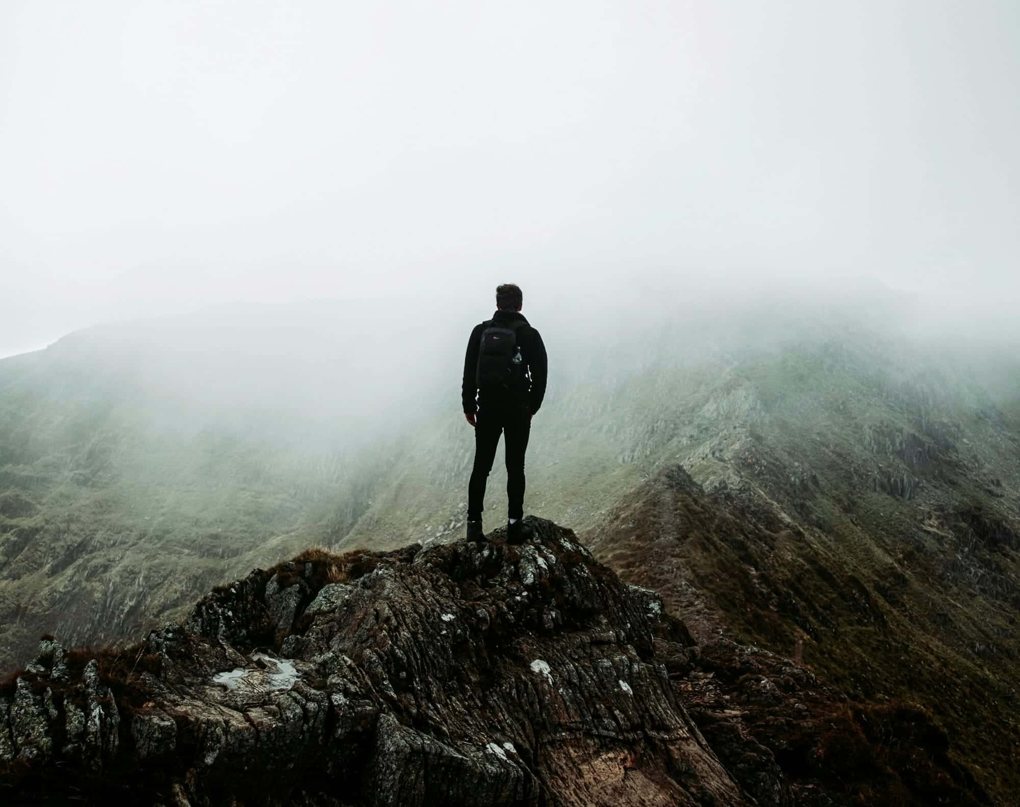 A man standing on a mountain ridge in fog